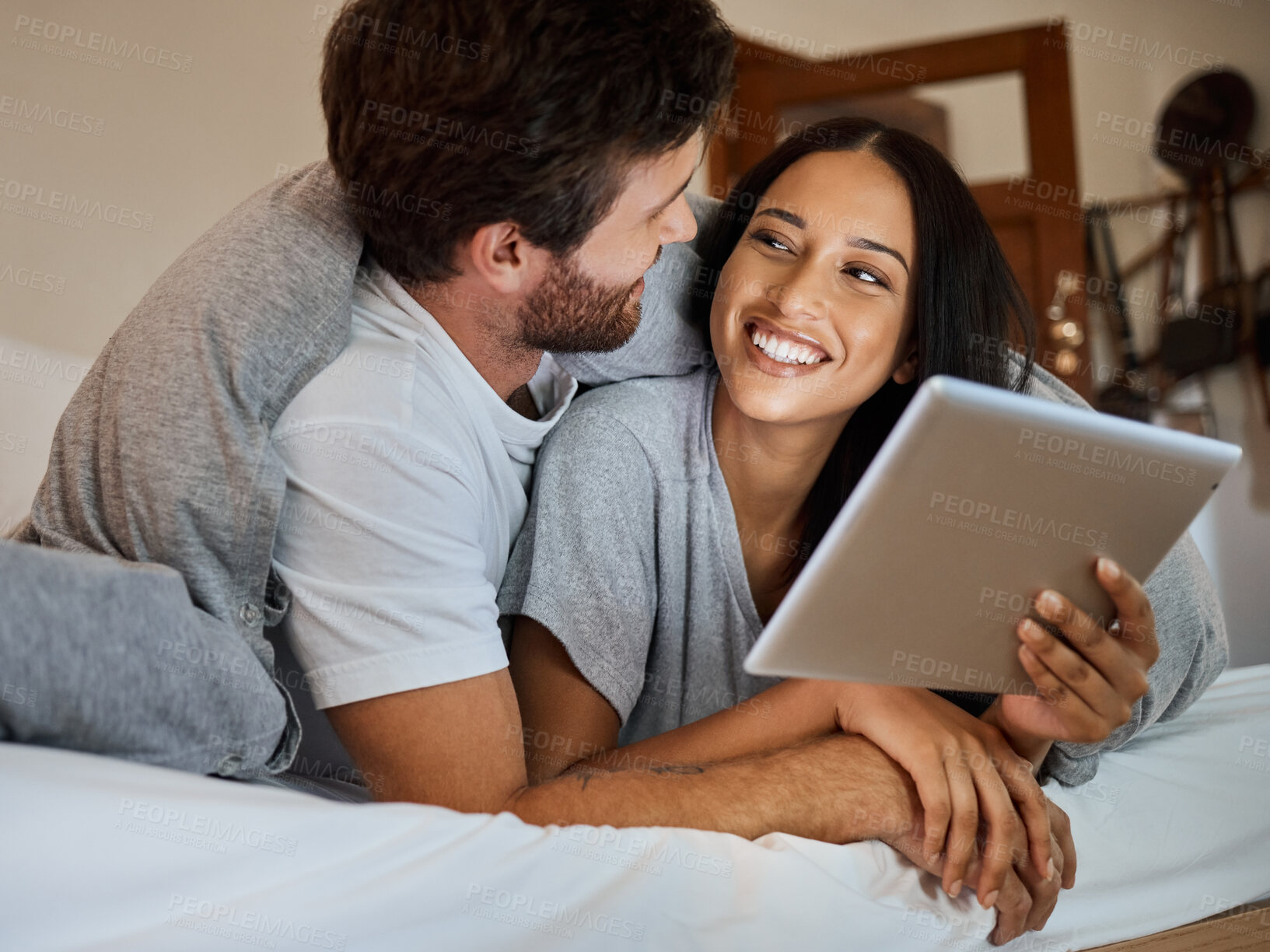 Buy stock photo Happy couple, smile and tablet in bedroom entertainment, love and care relaxing together at home. Man and woman smiling for fun bonding time streaming on wifi in bed with touchscreen technology