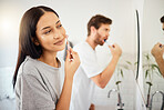 Makeup, face and beauty with a woman using cosmetics in the bathroom at home with her man in the background. Cosmetic, skin and care with an attractive young female and her boyfriend in their house 