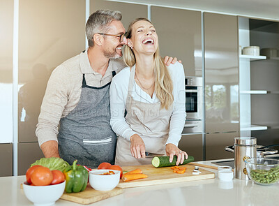 Buy stock photo Couple in kitchen cooking together in their home, having fun and laughing. Middle aged man and woman cutting healthy vegetables and making food in their house. Smiling, happy and in love people
