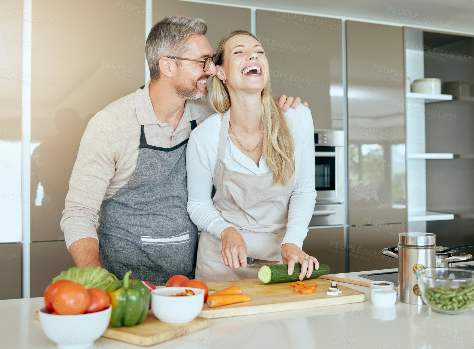 Buy stock photo Couple in kitchen cooking together in their home, having fun and laughing. Middle aged man and woman cutting healthy vegetables and making food in their house. Smiling, happy and in love people