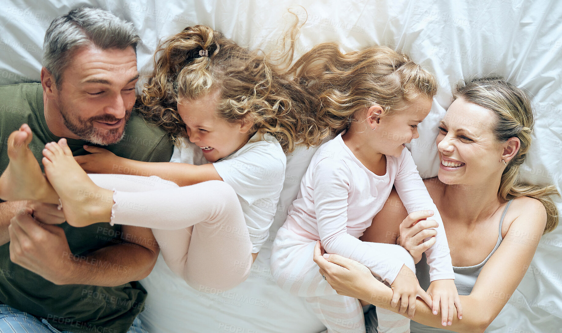 Buy stock photo Happy, family and children with a smile in a home bedroom bed spending quality time together. Young girl kids, mother and man at a house with happiness and crazy fun laughing with and playing