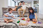 Family home, parents and children with toys on carpet in living room for holiday with mother and father love, care and happiness. Relax mom, dad on couch while baby or kids play together on the floor