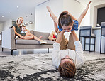 Father with girl on carpet floor and mother relax with baby on sofa in home living room for family love, care and wellness. Happy kid play fun youth game with dad and parents bonding in house lounge
