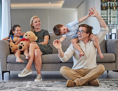 Buy stock photo Happy family, children playing and caring mom and dad having fun while bonding, love and sitting together in the lounge at home. Man, woman and kids in house to relax, smile and enjoy time on weekend
