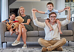 Relax, family and sofa portrait in home with young parents and children bonding on the weekend. Playful, piggy back and happy people with kids enjoy cheerful time together in house living room.

