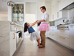 Love, father and child holding hands with feet balance game  for fun in family home together. Care, love and support of young dad bonding with daughter in kitchen with ballet tutu costume.