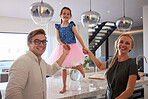 Girl dance on table, parents hold her hands and smile together in home kitchen. Happy family in house, mom and dad laughing while female child with ballet skirt dancing barefoot on marble countertop