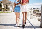 Girl friends walk on boardwalk in summer next to beach, nature and ocean during holiday. Interracial lgbtq couple holding each other while enjoy walk close to water and sand on a seaside vacation.