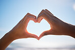 Heart sign, beach hands and blue sky on vacation by the sea, happy on international holiday in Miami and love for summer travel in nature. Person with emoji for happiness by the ocean in spring