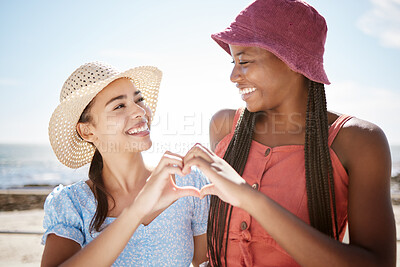 Buy stock photo Happy interracial friends, smile and heart hand sign for love, beach and outdoor freedom together on summer vacation. Women couple in loving shape gesture for friendship happiness and joy on holiday
