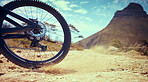 Bike, sport and adventure with a bicycle wheel in the dirt for adventure, risk or freedom and a mountain in the background. Bicycle, track and sports with a tyre turning in the sand for fun and speed