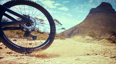 Buy stock photo Bike, sport and adventure with a bicycle wheel in the dirt for adventure, risk or freedom and a mountain in the background. Bicycle, track and sports with a tyre turning in the sand for fun and speed