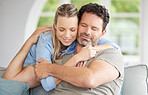 Couple, love and hug with a man and woman hugging in the living room of their home. Relax, together and happy with a female and male embracing for romance and bonding while sitting on the house sofa
