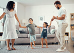 Happy family, dancing and having fun while sharing love, energy and bond while holding hands in the living room at home. Man, woman and sibling kids playing and laughing enjoying active time together