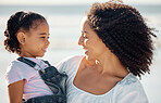 Mom with child at beach smile, make eye contact and show expression of happiness. Black woman with girl, happy spend time as mother and daughter, on family holiday or vacation by the ocean