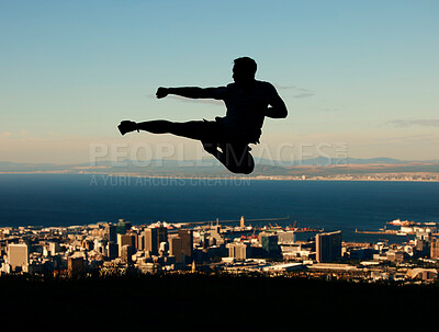 Silhouette of man doing karate with sky and city in the background. Outline of male athlete punching and kicking in the air in martial arts motion. Motivation, inspiration and urban warrior