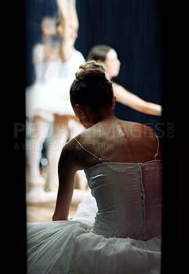 Buy stock photo A ballerina backstage of a performance at a theatre on stage. Ballet dancer sitting on the floor while play or concert is happening. She is getting ready, doing warm up and preparing to dance