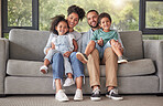 Happy family on sofa and portrait in their living room with lens flare for wellness, child development and quality time at home. Smile, love and care of interracial mother, father and kids on couch