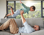 Relax, family and dad balance on sofa for fun bonding time together in cozy house in Mexico. Support, trust and love of Mexican father holding young child in air with arms in living room.

