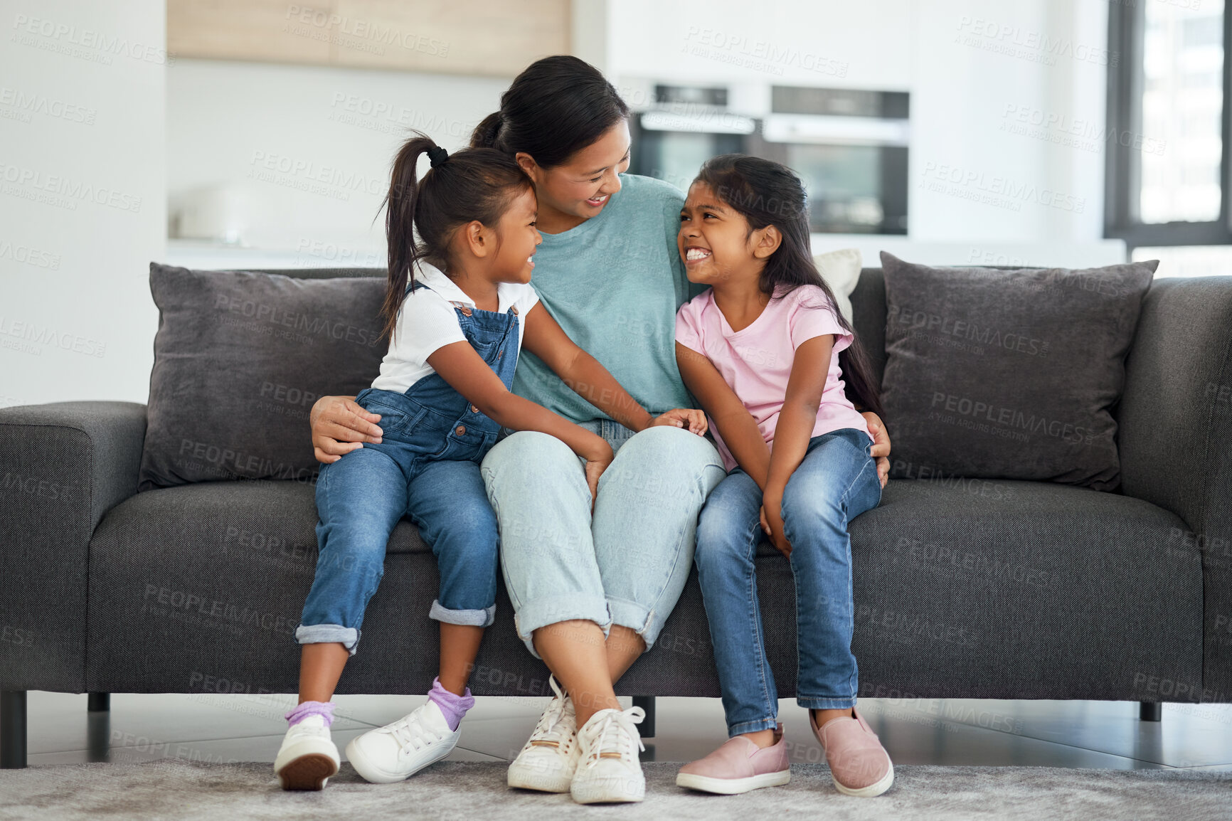Buy stock photo Family, love and single mother with kids looking happy, relax and smiling sitting together and bonding on sofa in lounge at home. Asian babysitter woman hugging cute girls, daughters or twin sisters