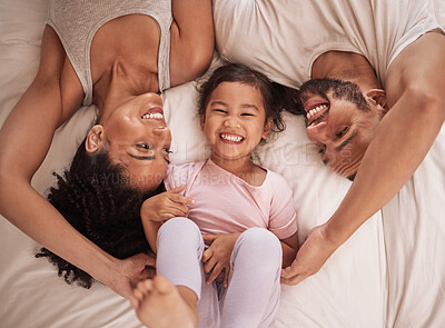 Buy stock photo Above, family and child happy on bed smile, laugh and bonding on weekend. Mom, dad and parents with kid in pajamas enjoying quality time, being playful and fun together in bedroom in the morning. 