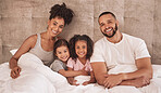 Portrait of happy latin family bonding on a bed, carefree, relax and rest in a bedroom together. Young loving parents enjoying free time with their children or daughter and showing affection together