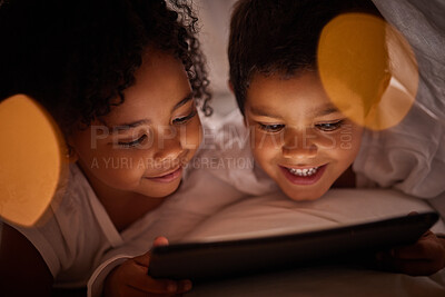 Buy stock photo Children learning on a digital tablet while bonding in bed at night, happy and relax while streaming together. Happy girl and boy awake late, enjoying online game and movie while resting indoors