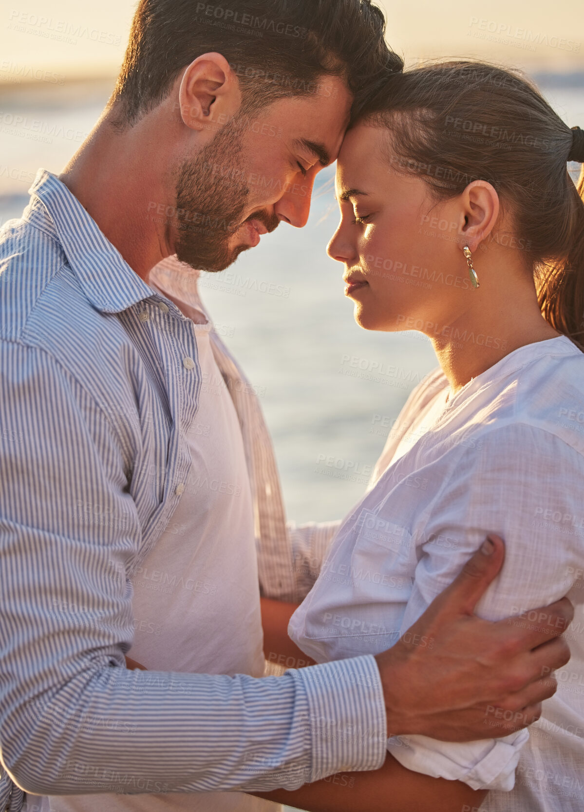 Buy stock photo Couple, sunset and beach for love together on holiday or honeymoon. Man, woman and ocean in embrace for romance, during vacation, trip or travel by the sea in late summer sunlight show happiness