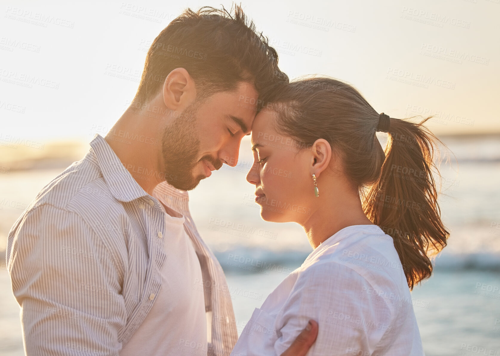 Buy stock photo Sunset, love and couple at the beach while on holiday or romantic summer honeymoon in greece. Happy, care and calm man and woman with romance, embracing and bonding in nature by the ocean on vacation