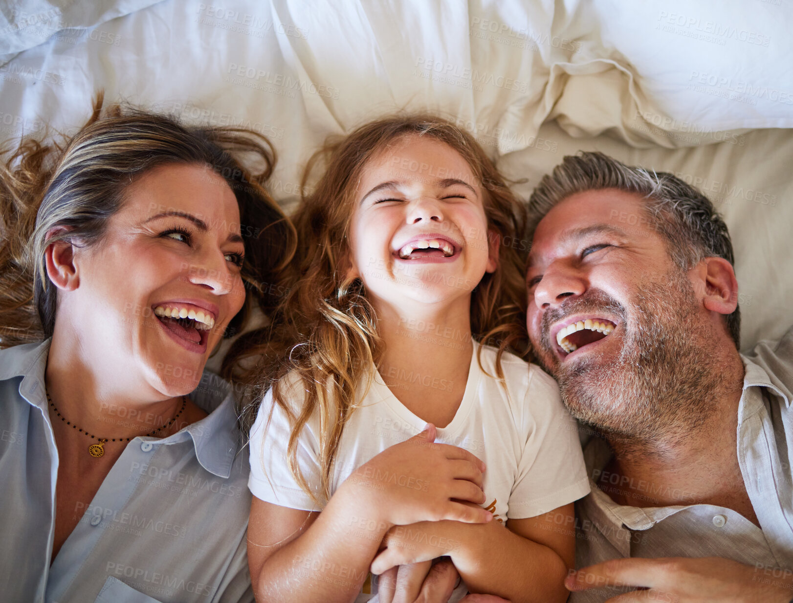 Buy stock photo Mother, father and child happy in bed together in the morning, laughing at joke and bonding in house. Family with love in home bedroom, being funny and smile for comedy while relax with girl