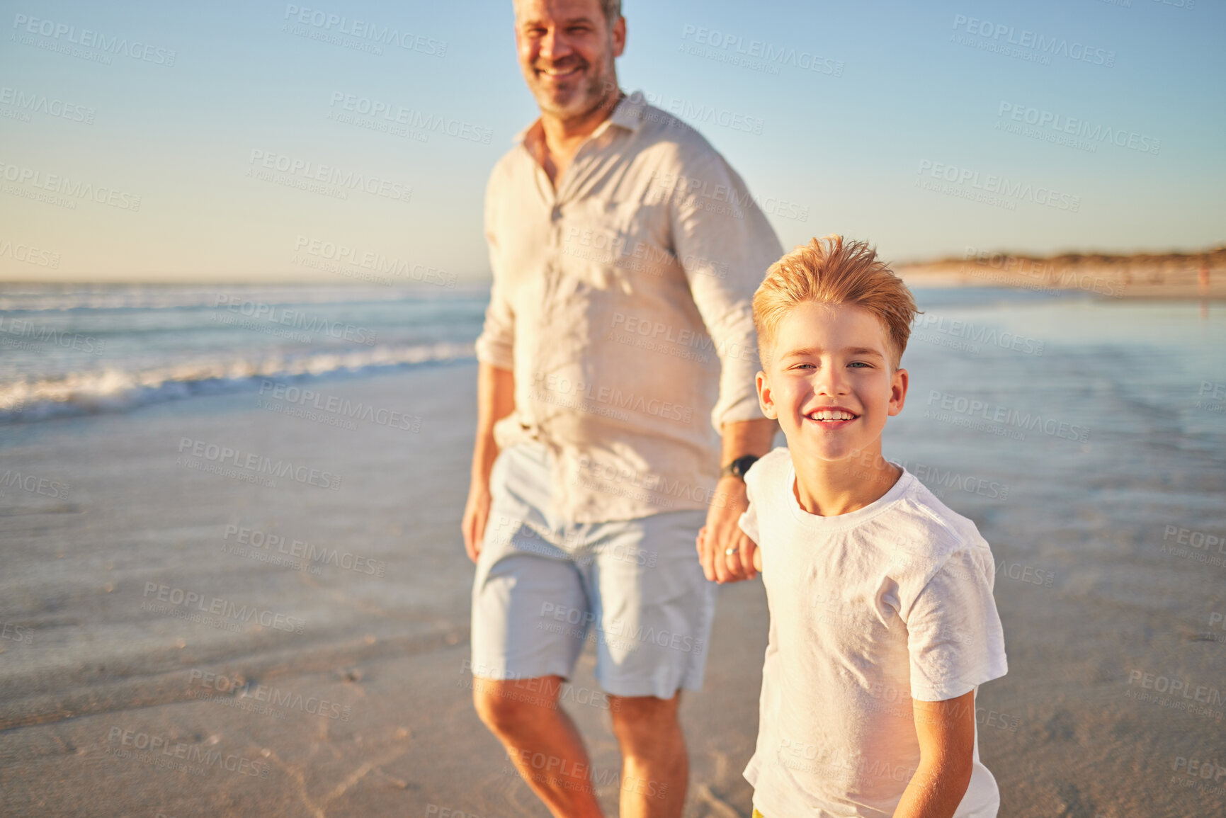 Buy stock photo Father and son bonding on a beach, walking alone the ocean and holding hands at sunset. Portrait of an excited child enjoying and ocean trip and peaceful walk with a loving, caring parent in nature