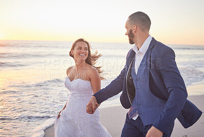 Buy stock photo Couple, wedding and beach smile in sunset on romantic walk together after getting married. Happy, wife and man in suit walking at ocean, romance and marriage after ceremony with sun setting over sea