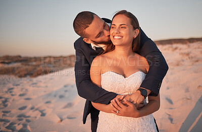 Buy stock photo Wedding, couple and beach love with a kissing bride and groom on the beach at sunset after a ceremony or celebration. Happy, kiss and marriage with a man and woman hugging on the sand during summer