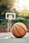 A ball used for basketball on an outdoor basketball court in a park. Mockup for sport, training and getting ready to play a match for exercise. Summer, sports and playing games outside to keep fit