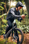 Fitness, phone and forest cyclist in nature and sustainability New Zealand woods with gps location, health data and tracking app. Smile, happy and training sports biker with helmet and 5g mobile tech
