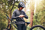 Time, bicycle and man cycling in nature checking his stopwatch in a cardio workout, training and exercise outdoors. Fitness, forest and healthy person proud of his bike riding in the natural woods 