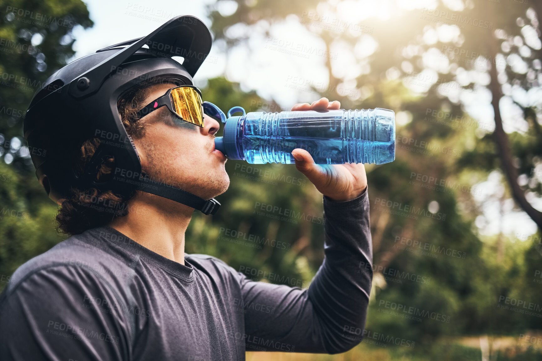 Buy stock photo Cyclist, water and bottle in forest for hydration, with cycling equipment and sunglasses by trees for wellness. Man, drink and sports while exercise, workout or training for fitness outside in woods