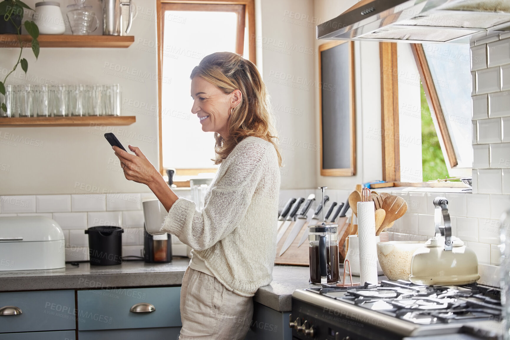 Buy stock photo Mature woman reading phone news, social media notification and mobile apps in Australia kitchen home. Happy lady typing smartphone, online social network and 5g web technology connection in apartment