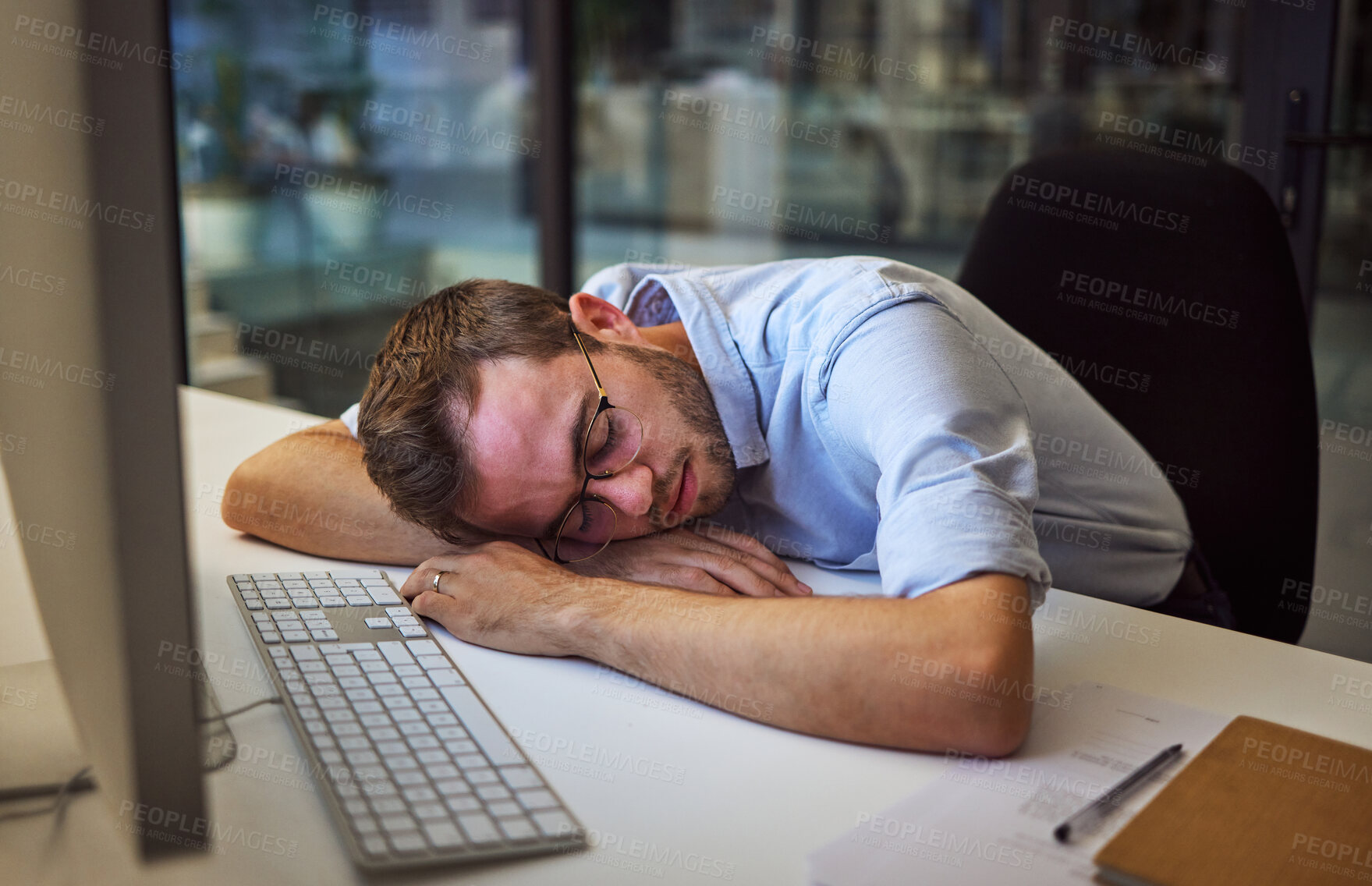 Buy stock photo Burnout, tired and sleep with a business man sleeping on his desk while working on a computer at a desk in his office. Mental health, problem and exhausted with a young male employee at work at night