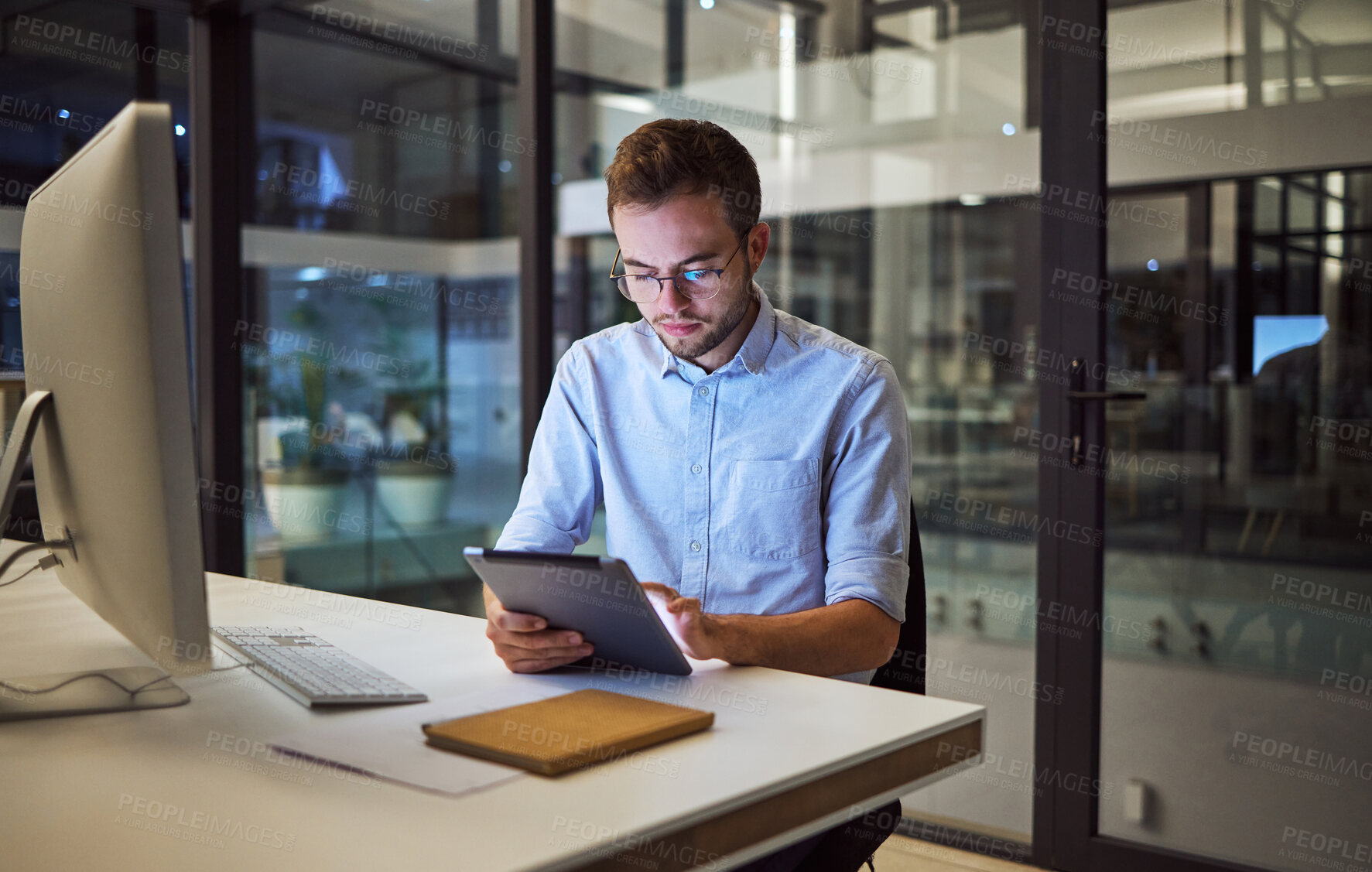 Buy stock photo Business, communication and overtime, man with tablet and computer at desk. Late night at office, working on deal or internet project. Corporate worker in glasses, checking online financial report.