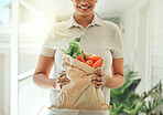 Healthy food, delivery and vegetables in brown grocery paper bag for clean vegan diet with fresh organic ingredients in hands of woman standing at home. Nutrition, vegetarian and health of a female