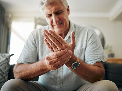 Buy stock photo Hands, pain and arthritis with a senior man holding his hand while suffering from osteoporosis, cramp or injury. Health, medical and joint with an elderly male pensioner in the living room at home