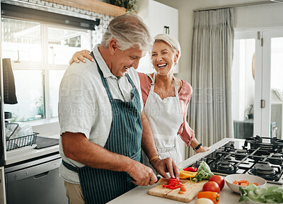 Buy stock photo Senior couple, cooking and having fun while preparing a healthy food with vegetables for a vegan meal in the kitchen at home while laughing and having fun. Funny old man and woman helping with dinner