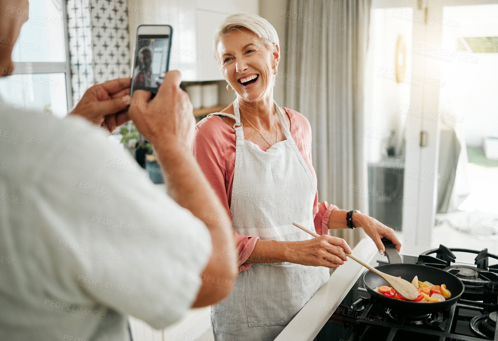 Buy stock photo Phone, man and woman taking a picture and cooking healthy food for dinner in a kitchen in a happy home. Smile, social media and elderly couple love having fun, memories and enjoying quality time