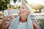 Senior fitness woman drinking water bottle outdoors after training, running workout and exercise in neighborhood street. Thirsty elderly lady runner hydration rest for cardio wellness or marathon jog