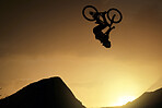 Cyclist, fitness and stunt jump at sunset in Colorado countryside nature mountains in fitness, exercise or training. Danger risk, extreme sports mountain bike or freedom man in sunrise energy workout