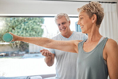 Buy stock photo Fitness, health and senior couple doing exercise in the living room of their comfortable home. Happy, smile and healthy elderly woman doing arm workout with motivation from her husband in retirement.