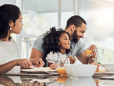Buy stock photo Happy family, breakfast and eating at table in home, talking or discussion together. Love, support and comic man, woman and girl child laughing, care and bonding drinking orange juice and having food