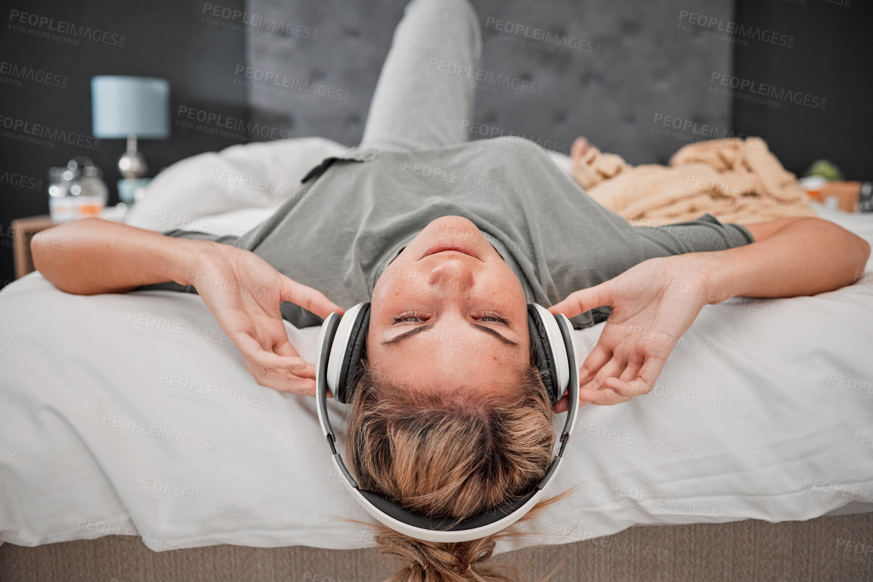 Buy stock photo Sleep music, bed and woman listening to audio podcast with headphones in the bedroom of her house. Sleeping girl streaming calm radio sound for peace, relax and content mind with wifi in home