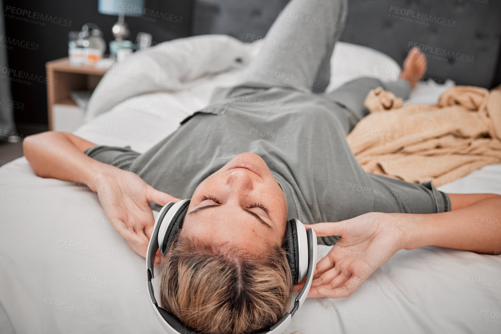 Buy stock photo Relax on bed, woman with headphones and streaming music online. Radio, podcast and content for entertainment on the internet. Girl with free time listening on earphones in bedroom at home in peace.